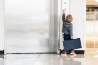 Child with briefcase points to an elevator.