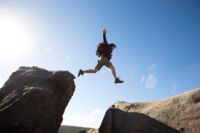 CANCOM Austria employee doing extreme sports climbing, jumping off a cliff in the great outdoors.